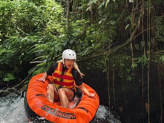 Una mujer gritando de emoción mientras desciende por los rápidos del río en un neumático naranja.