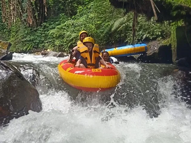 Une femme et un enfant naviguant dans des rapides à bord d’un radeau jaune sur la rivière Pakerisan.
